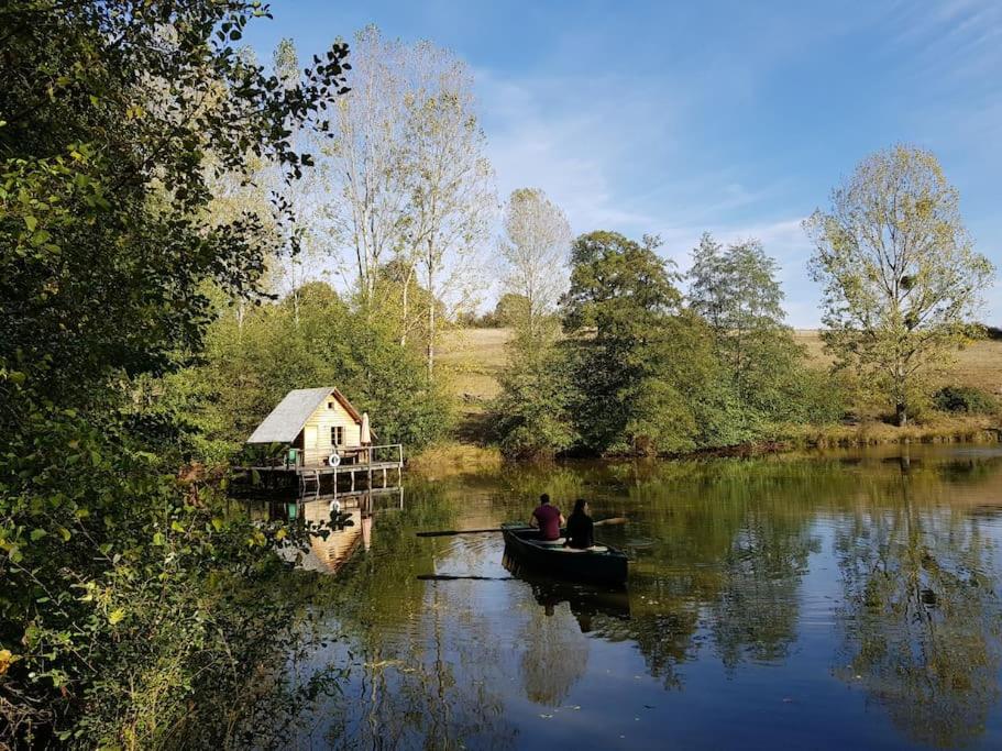 2 personnes dans un bateau sur une rivière avec une maison dans l'établissement Cabane sur Pilotis - Les Demoiselles, à Saint-Didier-sur-Arroux