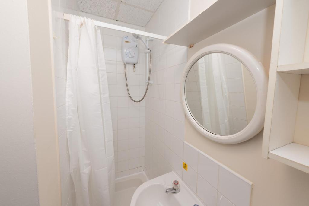 uma casa de banho branca com um chuveiro e um espelho. em Standard En-suite Apartment 2 em Plymouth
