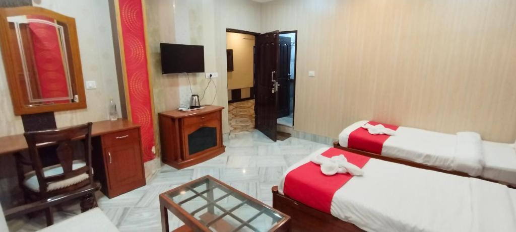 um quarto de hotel com duas camas e uma televisão em HOTEL RIZ VARANASI em Varanasi