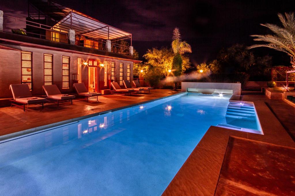 a swimming pool in front of a house at night at La Ferme de LallaDom in Tameslouht