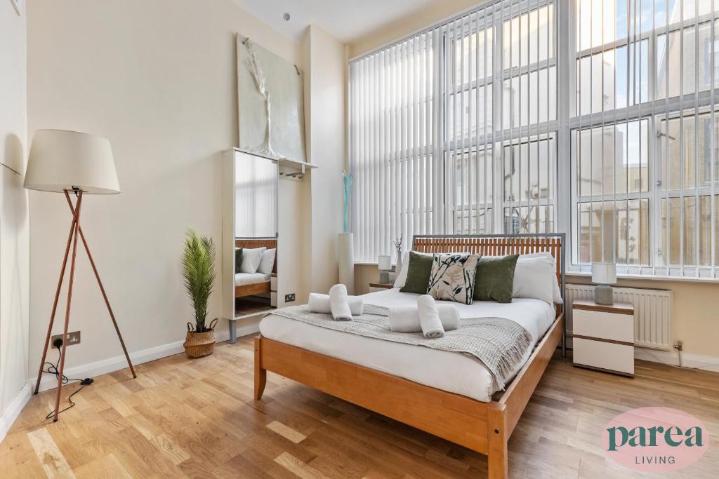 1 dormitorio con 1 cama en una habitación con ventanas grandes en Parea Living - Canary Wharf, Secluded Luxury Flat w Free Parking & Remote Working en Londres