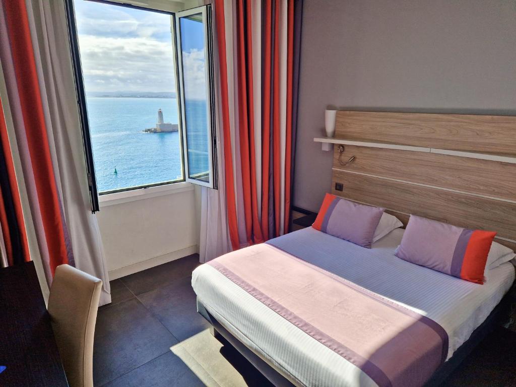 a bedroom with a bed and a large window at Hotel Le Saint Paul in Nice