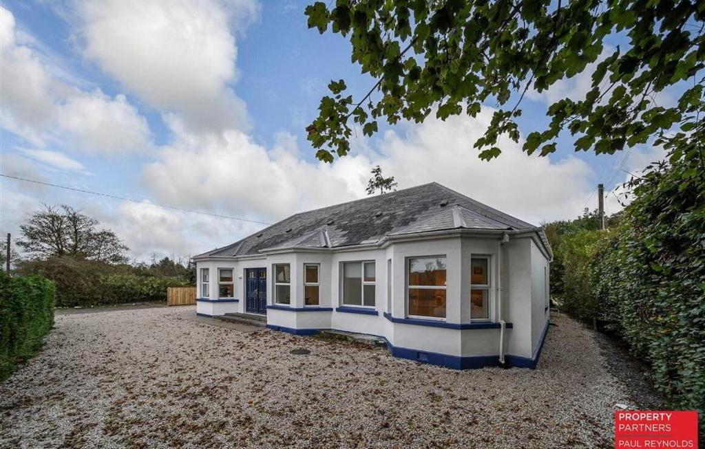 a small house sitting on top of a gravel driveway at Portsalon Cottage in Portsalon