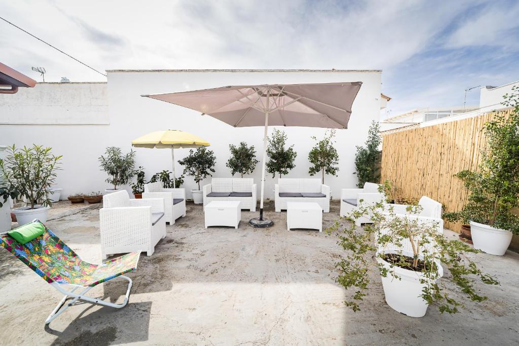 eine Terrasse mit weißen Stühlen und einem Sonnenschirm in der Unterkunft Villetta Iris by Vivimy in Taviano