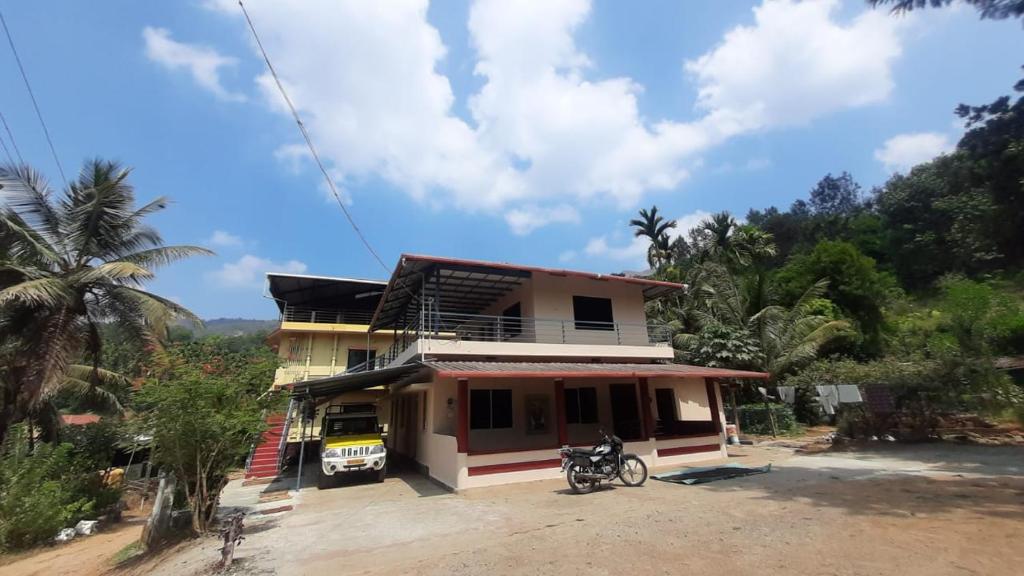 a house with a motorcycle parked in front of it at Samruddi Homestay in Kalasa