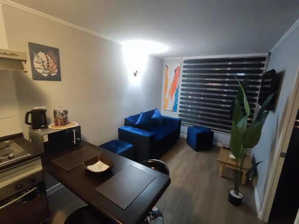 a living room with a table and a blue couch at Lindo y cómodo departamento a pasos del metro in Santiago