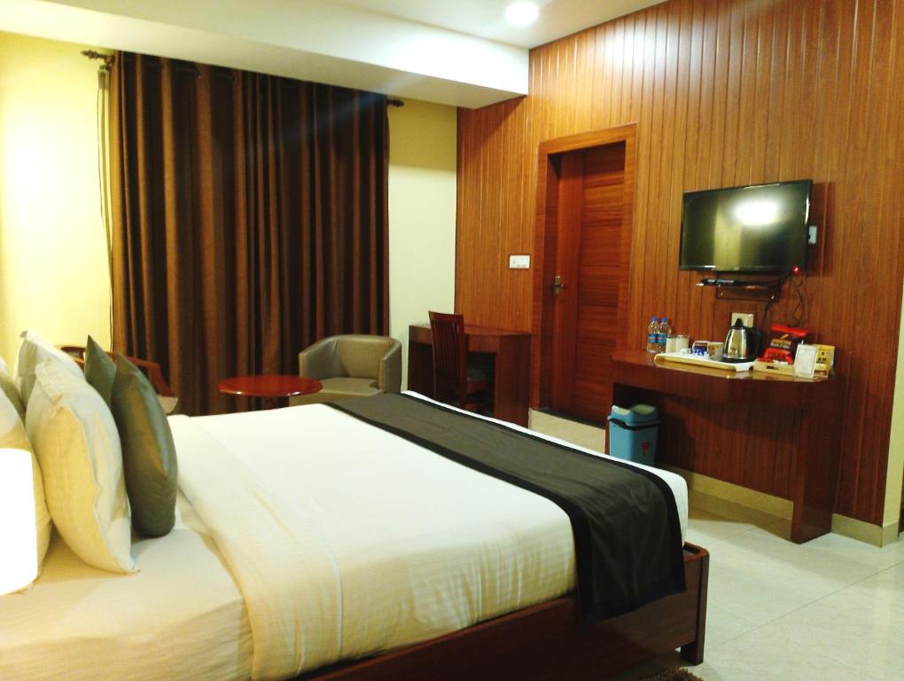 a hotel room with a bed and a flat screen tv at Hotel Ballerina in Tinsukia