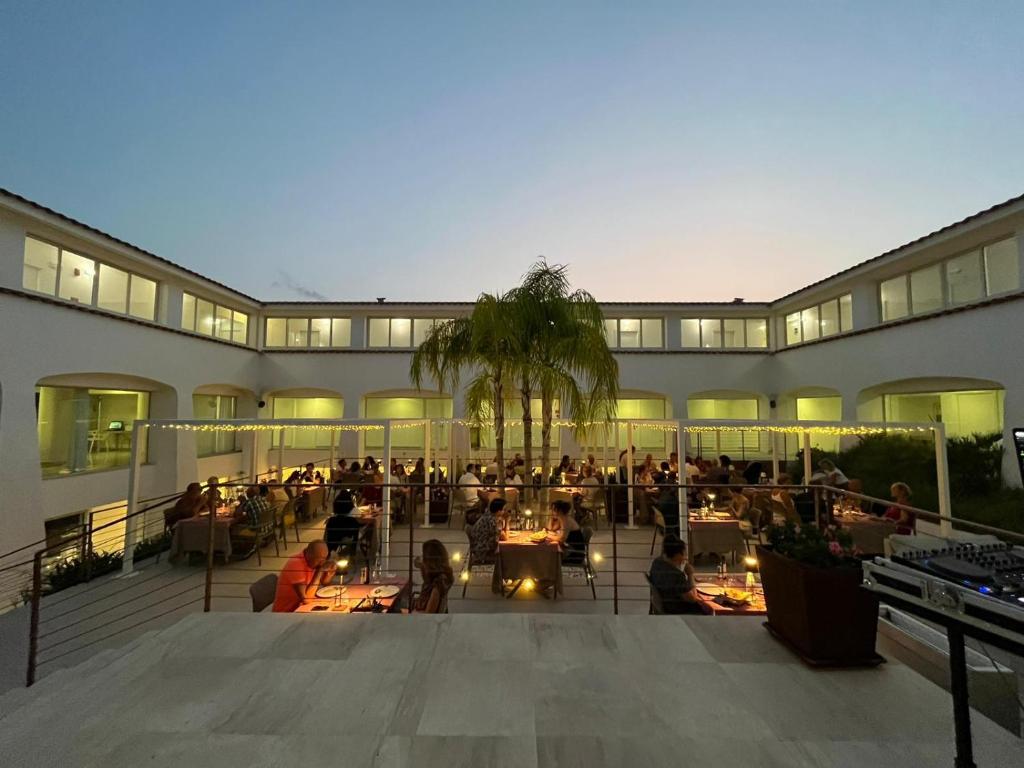 a building with people sitting at tables in a courtyard at Hotel San Teodoro in San Teodoro