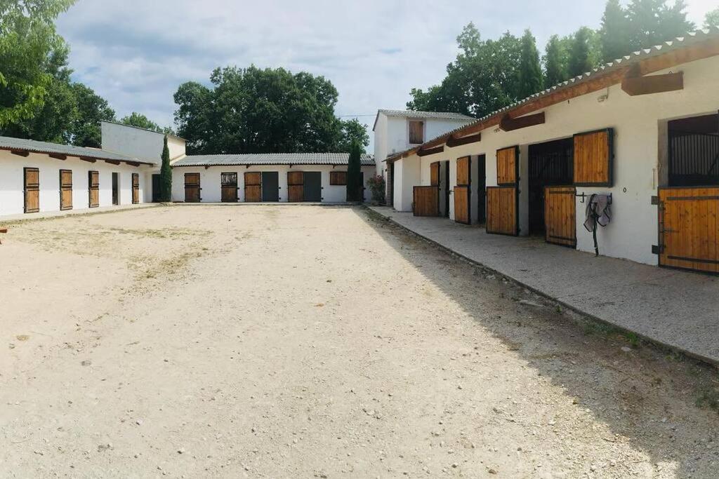 een lege parkeerplaats voor sommige gebouwen bij Maison au milieu des chevaux in LʼIsle-sur-la-Sorgue