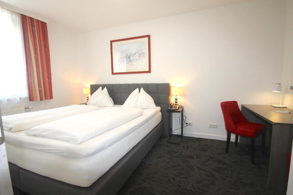 ウィーンにあるホテル アルトマンの大きなベッドと赤い椅子が備わるホテルルームです。