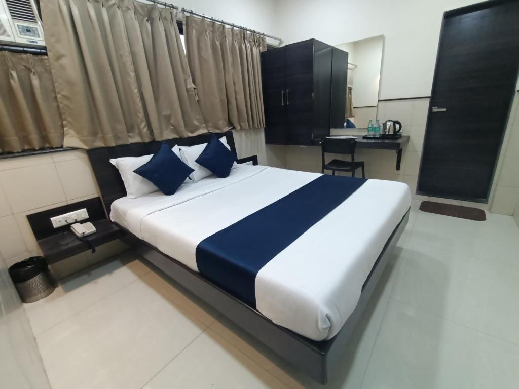 um quarto com uma cama grande e almofadas azuis e brancas em Hotel Triton - Near US Embassy em Mumbai