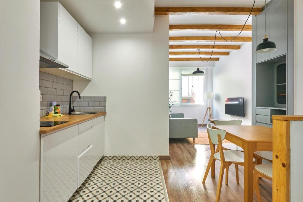 a kitchen with white cabinets and a wooden table at Ol Cute apartment in quiet Olivera st in Barcelona