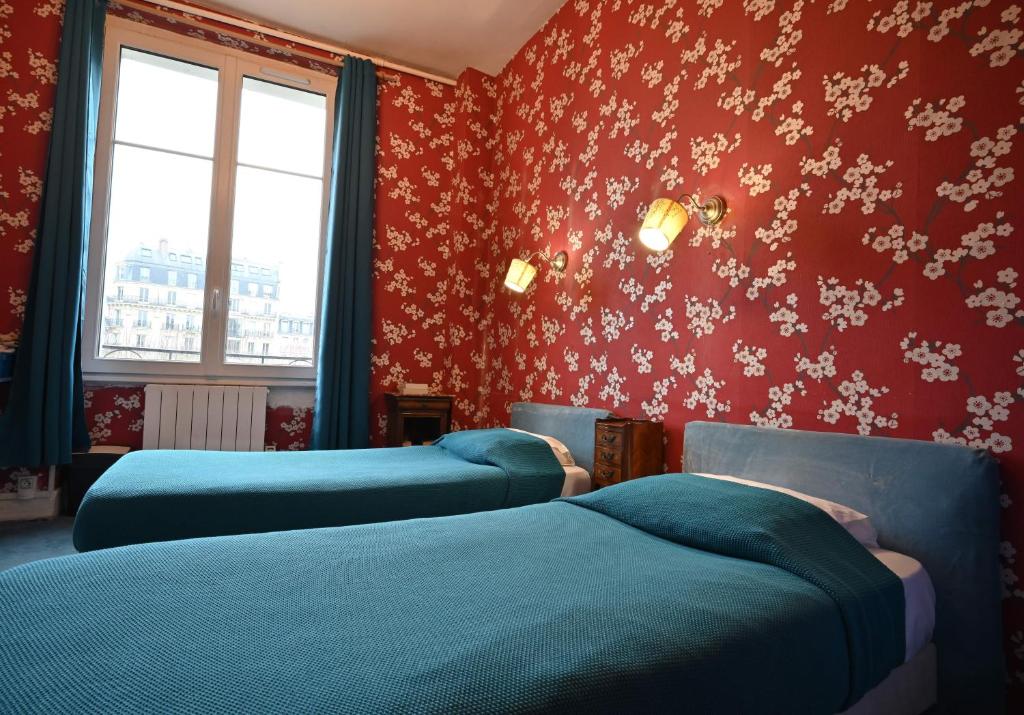 two blue beds in a room with red walls at Hotel Esmeralda in Paris
