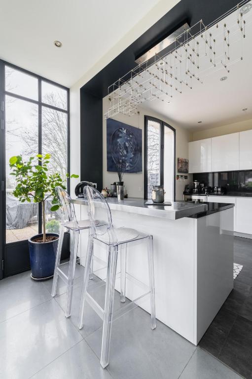 a kitchen with white chairs and a black and white counter at Wonderful luxury house at 10min from Paris in Meudon