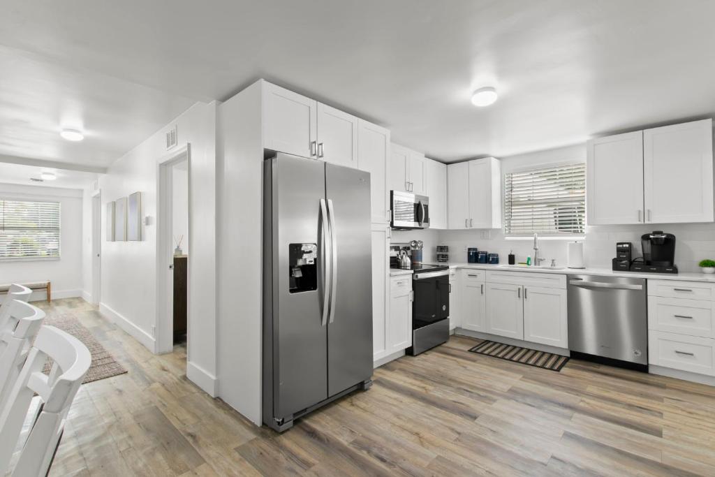 uma cozinha com armários brancos e um frigorífico de aço inoxidável em NEW St Pete Retreat - Newly Updated Pet Friendly em St. Petersburg