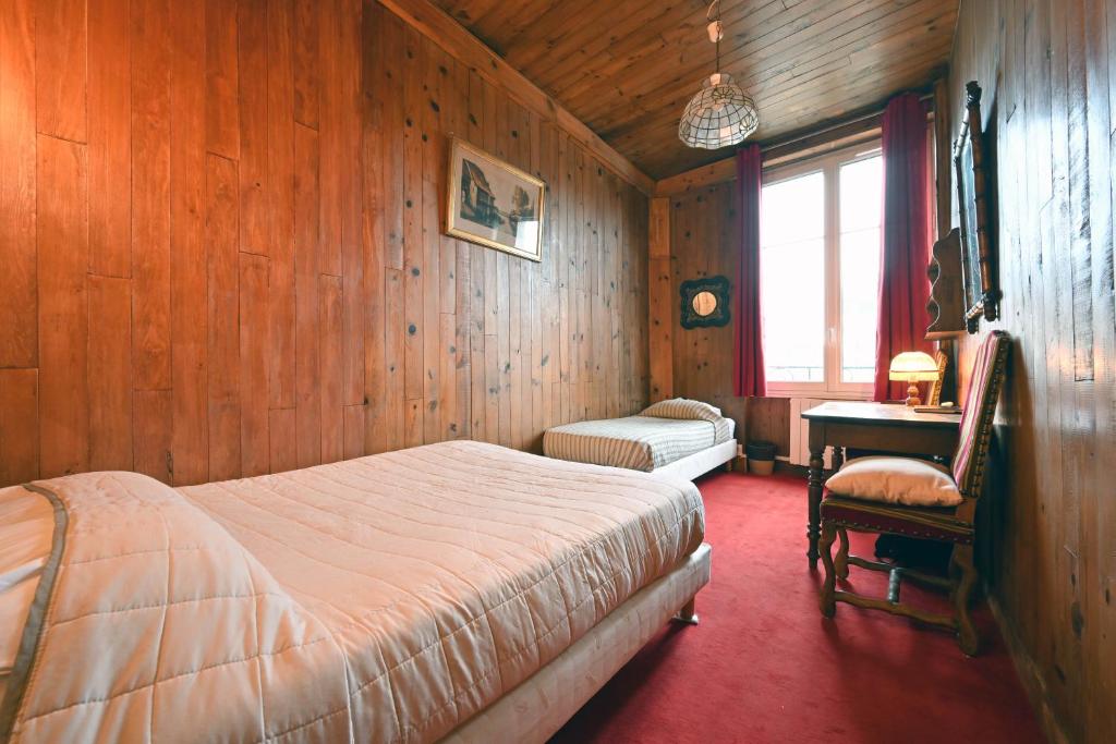 a bedroom with wooden walls and a bed and a desk at Hotel Esmeralda in Paris