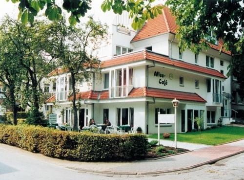 Une grande maison blanche avec des personnes assises devant elle dans l'établissement Gästehaus Bögemann, à Bad Rothenfelde