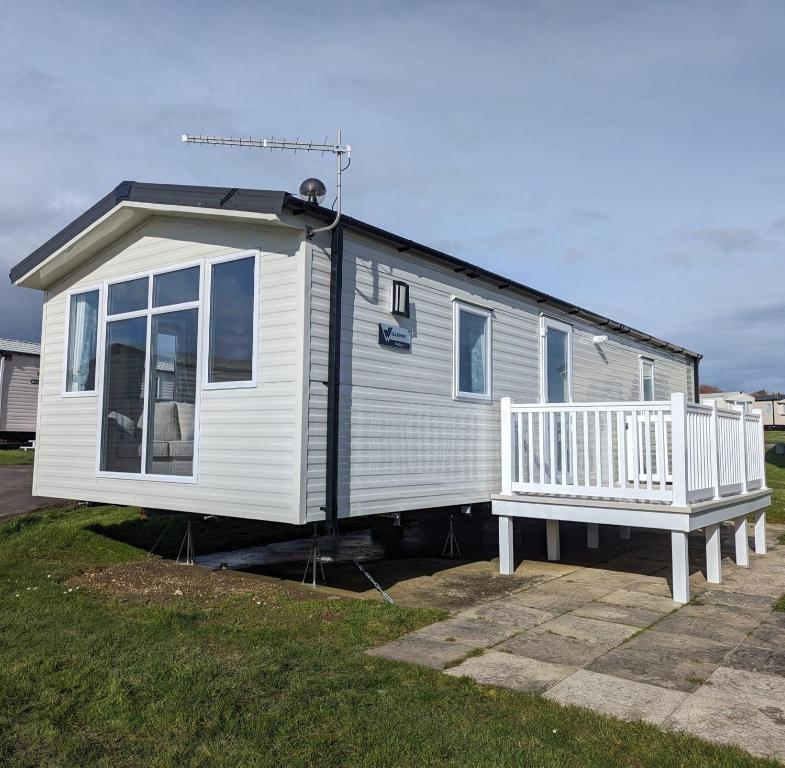 a small white house with a porch and a bench at Stylish Modern Bright Caravan with Views sleeps 6 Littlesea Haven Weymouth in Weymouth