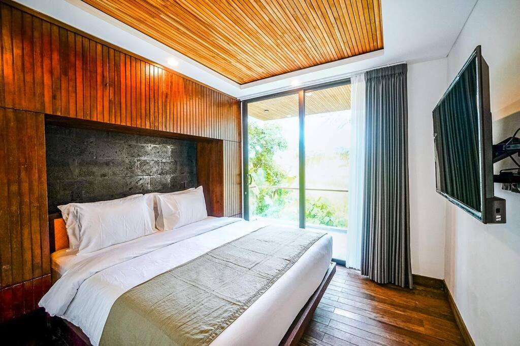 ein Schlafzimmer mit einem großen Bett und einem großen Fenster in der Unterkunft The Hitam Tiny Villa - 2 BR Architectural Villa 4 mins to Beach in Tanah Lot