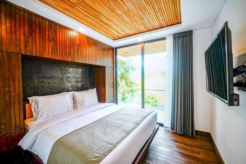 ein Schlafzimmer mit einem großen Bett und einem großen Fenster in der Unterkunft Tiny Villa Nyanyi - 2 BR Architectural Villa 4 mins to Beach in Tanah Lot