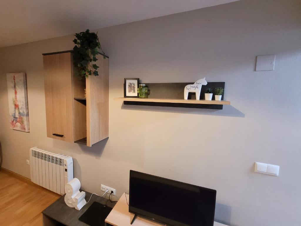 uma sala de estar com uma secretária e uma televisão na parede em Apartamentos Pedro Miñor em Oviedo