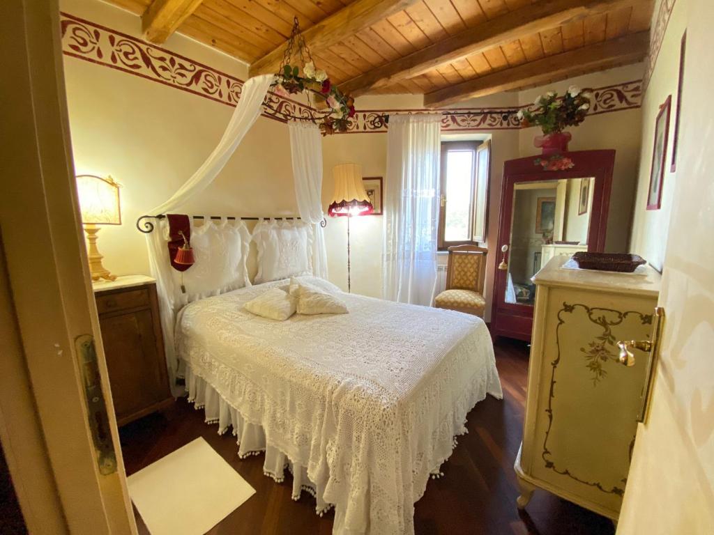 1 dormitorio con 1 cama blanca con dosel en Splendida villetta con giardino, en Barbarano Romano