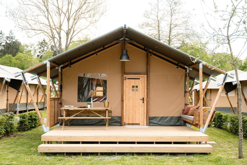 a tent with a wooden porch in a yard at Safaritent in Ingen