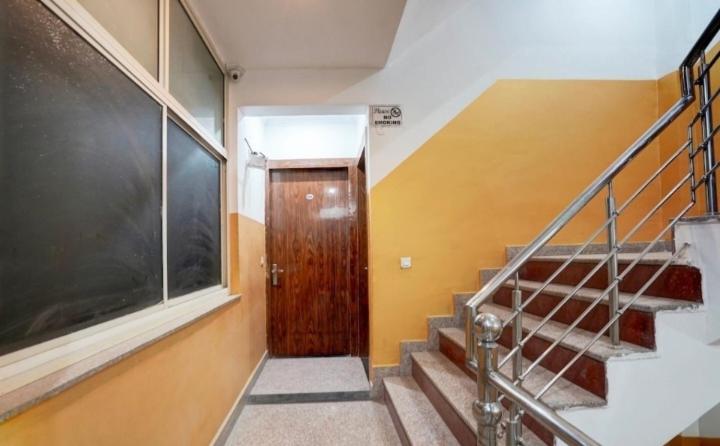 a hallway with a wooden door and stairs in a building at gold stays hotel near IGI international airport in New Delhi