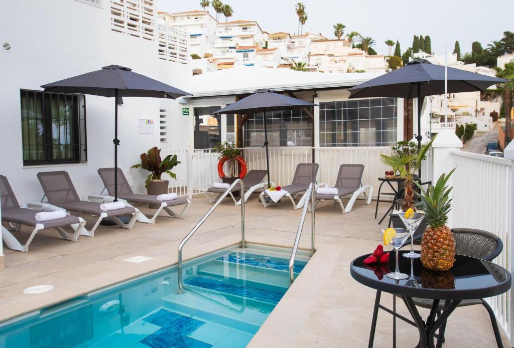 內爾哈的住宿－Boutique Rooms Playa Burriana，庭院内一个带椅子和遮阳伞的游泳池