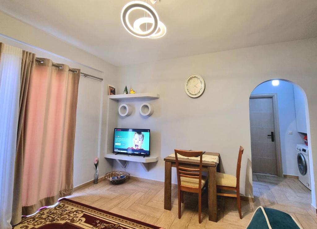 a living room with a table and a tv at Lea Apartament in Sarandë