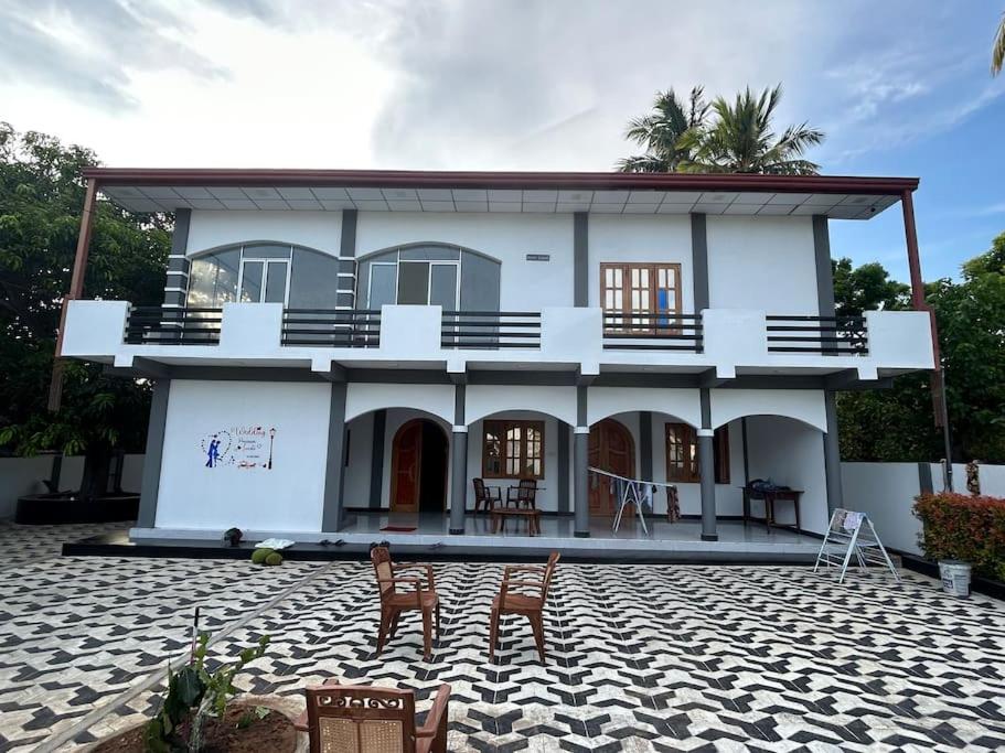 a white house with chairs in front of it at Augustin Guest House in Point Pedro