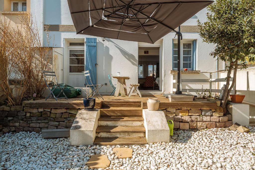 une terrasse avec un parasol et un mur en pierre dans l'établissement House Ty-Matelot Daleth at 2 min foot in the water, à Saint-Malo