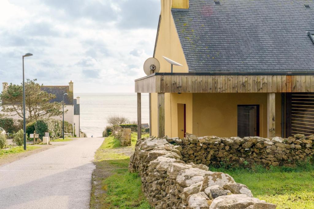 a building with a stone wall next to a road at Ty Jane Dour - Maison avec jardin in Plouhinec
