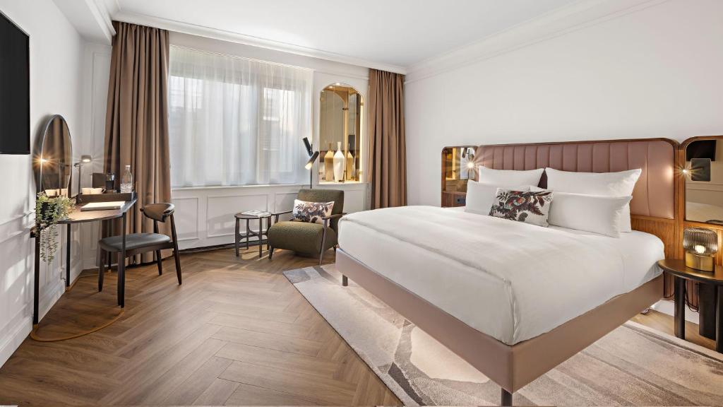 ベルリンにあるホテル ブリストル ベルリンの大きなベッドとデスクが備わるホテルルームです。