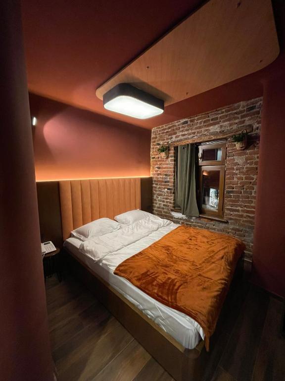 Cama grande en habitación con pared de ladrillo en New Soho Hotel, en Prizren