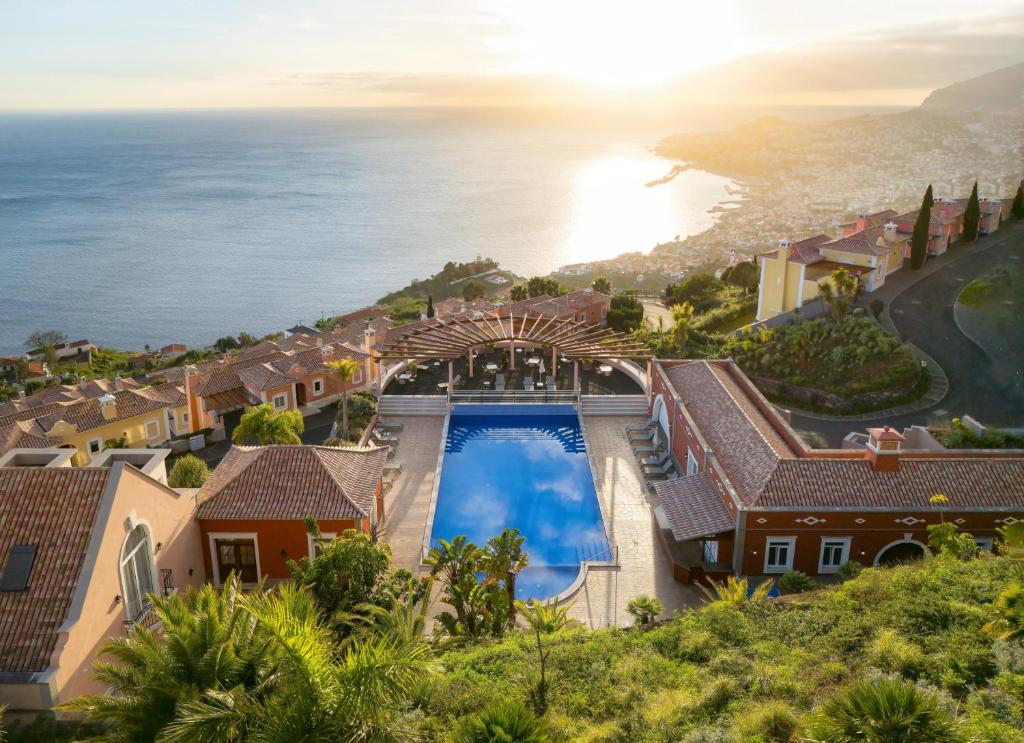 an aerial view of a house with a swimming pool and the ocean at Palheiro Village - Golf, Gardens & Spa in Funchal