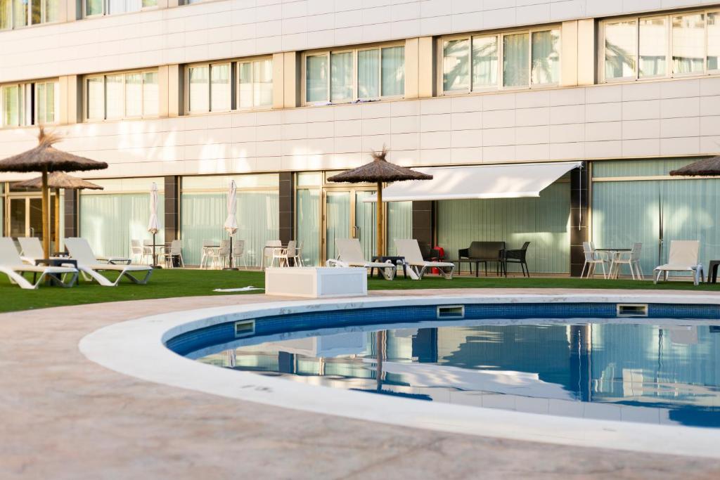 a swimming pool in front of a building with umbrellas at Daniya Alicante in Alicante