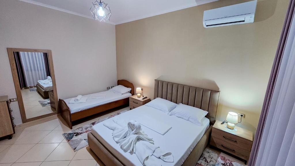 a small bedroom with two beds and a mirror at Guest House Edison in Berat