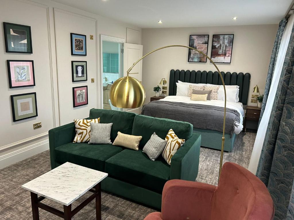 uma sala de estar com um sofá verde e uma cama em The Hillbrook Hotel & Spa - Sherborne em Sherborne