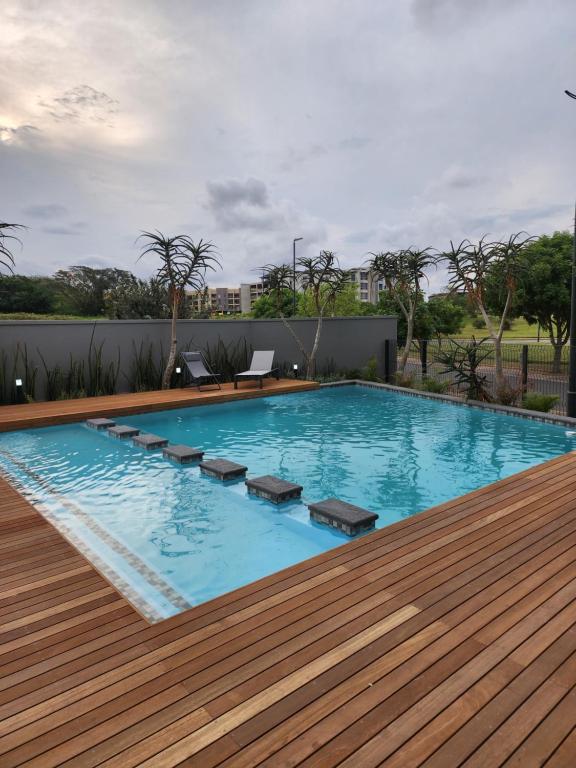 a large swimming pool with a wooden deck at Mkhonto-PR The Millenial Durban, Umhlanga in Durban