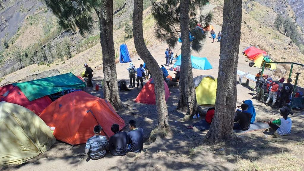 a group of people sitting around their tents in the woods at Joben Evergreen Camp Centre in Tetebatu