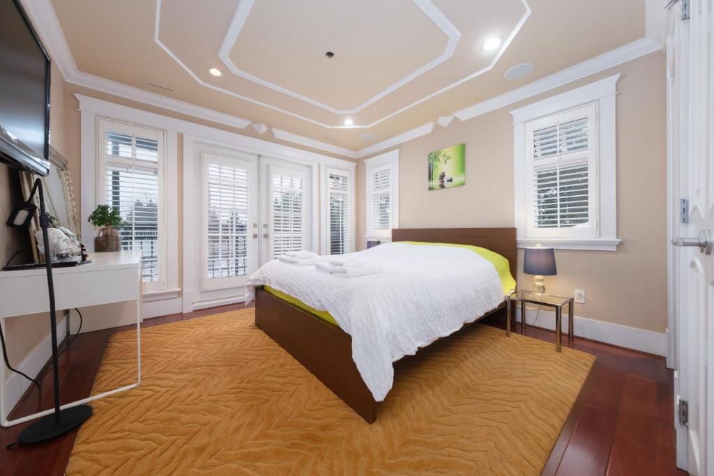 a bedroom with a bed in a room with windows at Oakridge Luxury Homestay in Vancouver