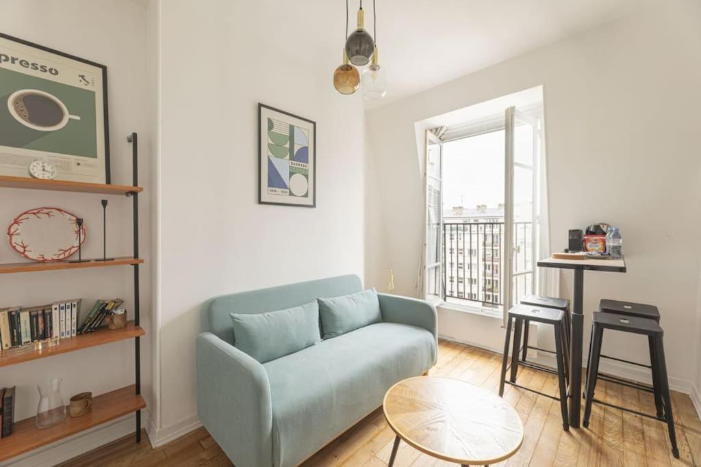 un salon avec un canapé bleu et une table dans l'établissement Apartment 1 Bedroom # Paris 14 # Alesia, à Paris