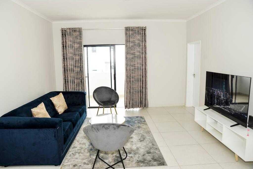 un soggiorno con un divano blu e una TV di The Ellipse Palazzo Apartment a Midrand
