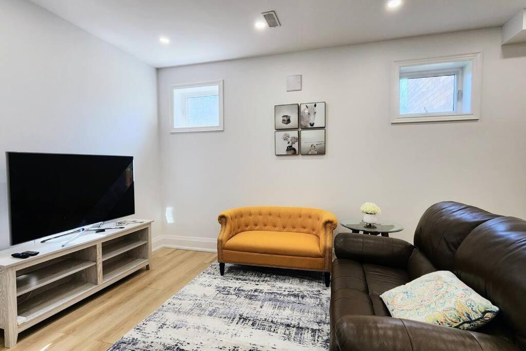 a living room with a leather couch and a flat screen tv at Serene High-celling Retreat in Oakville