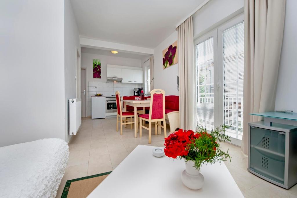 un soggiorno e una cucina con tavolo e fiori rossi di Apartments and Room Marko a Rovigno (Rovinj)