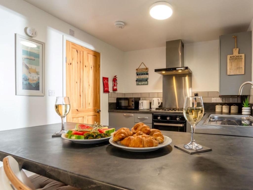 a kitchen with two plates of food and glasses of wine at Chalet Bushwood Lodge by Interhome in Helston
