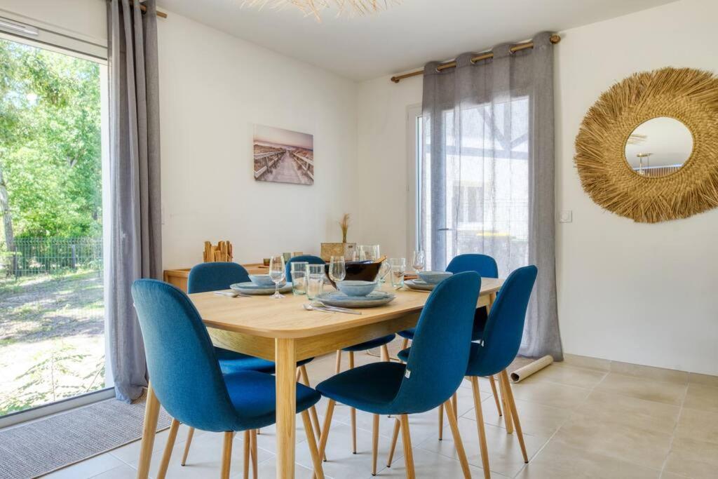 a dining room with a wooden table and blue chairs at Résidence Escale Bleue in Andernos-les-Bains