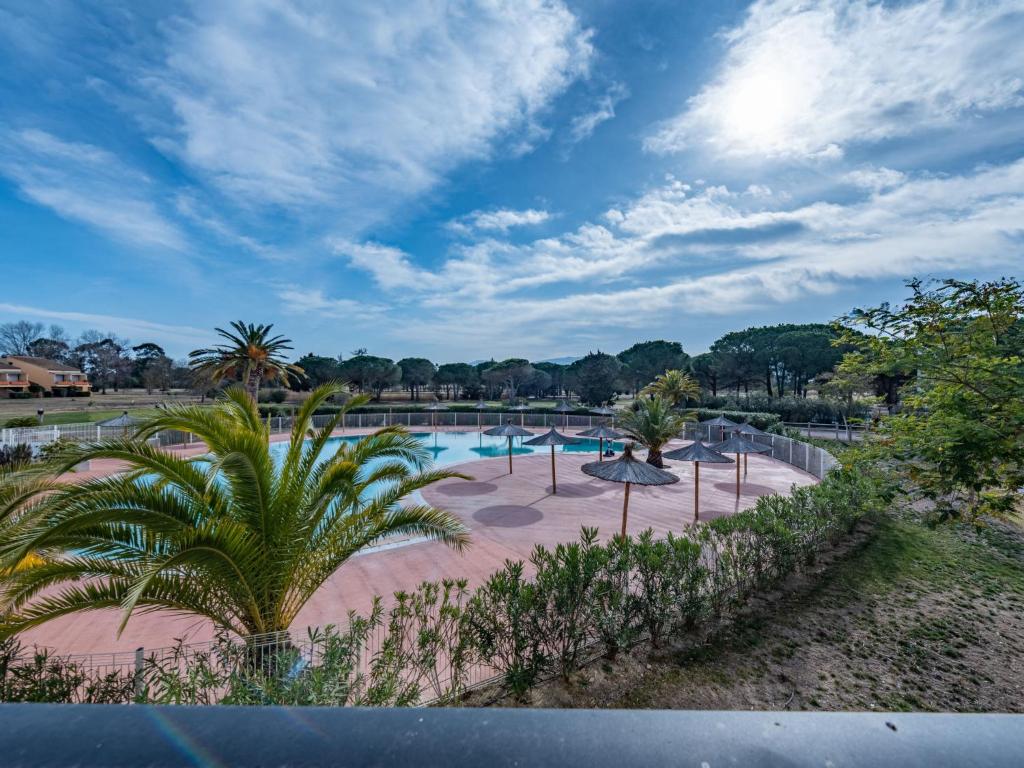 - une piscine dans un parc avec un palmier dans l'établissement Apartment Horizon Golf by Interhome, à Saint-Cyprien