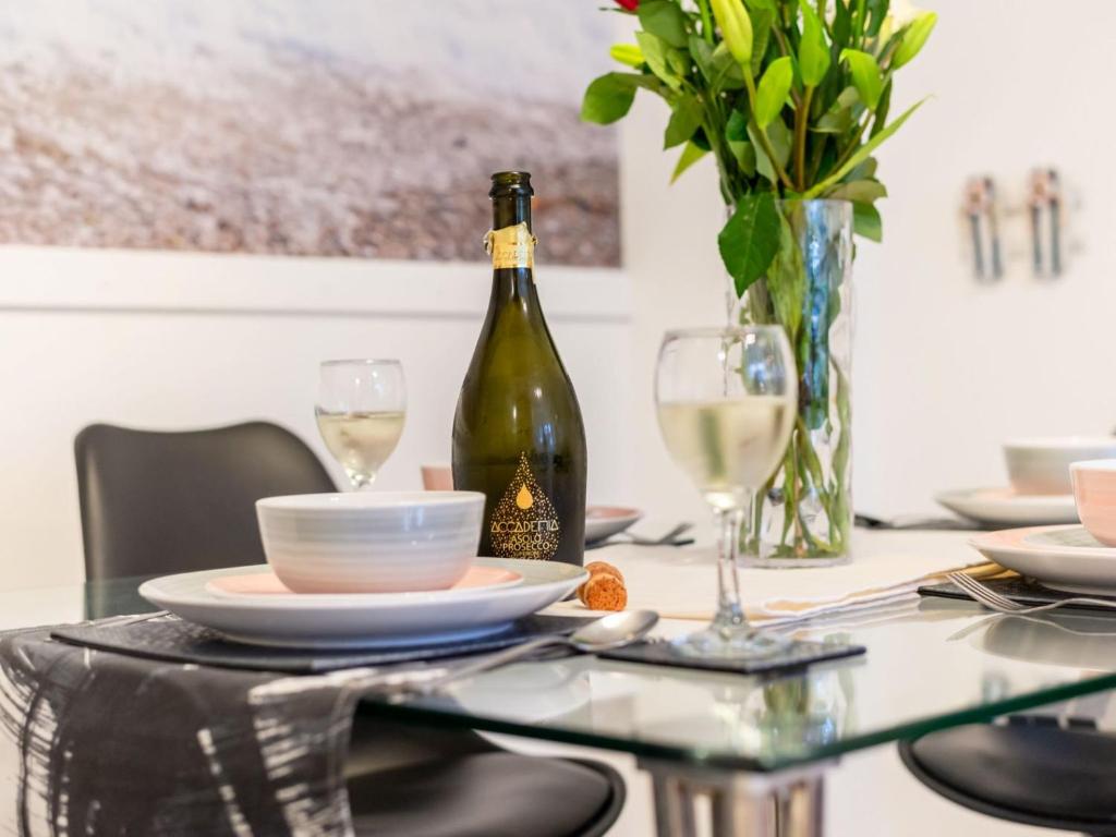 a dining table with a bottle of wine and glasses at Holiday Home Marshmallow House by Interhome in St Austell